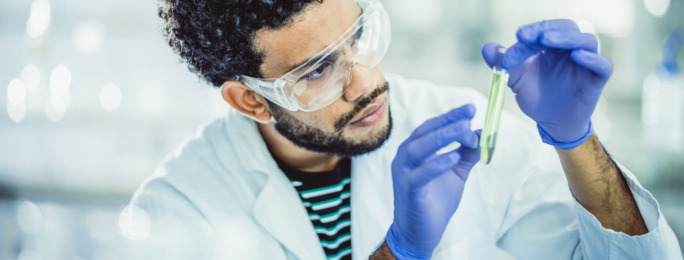 Medical professional with blue gloves, goggles and test tube