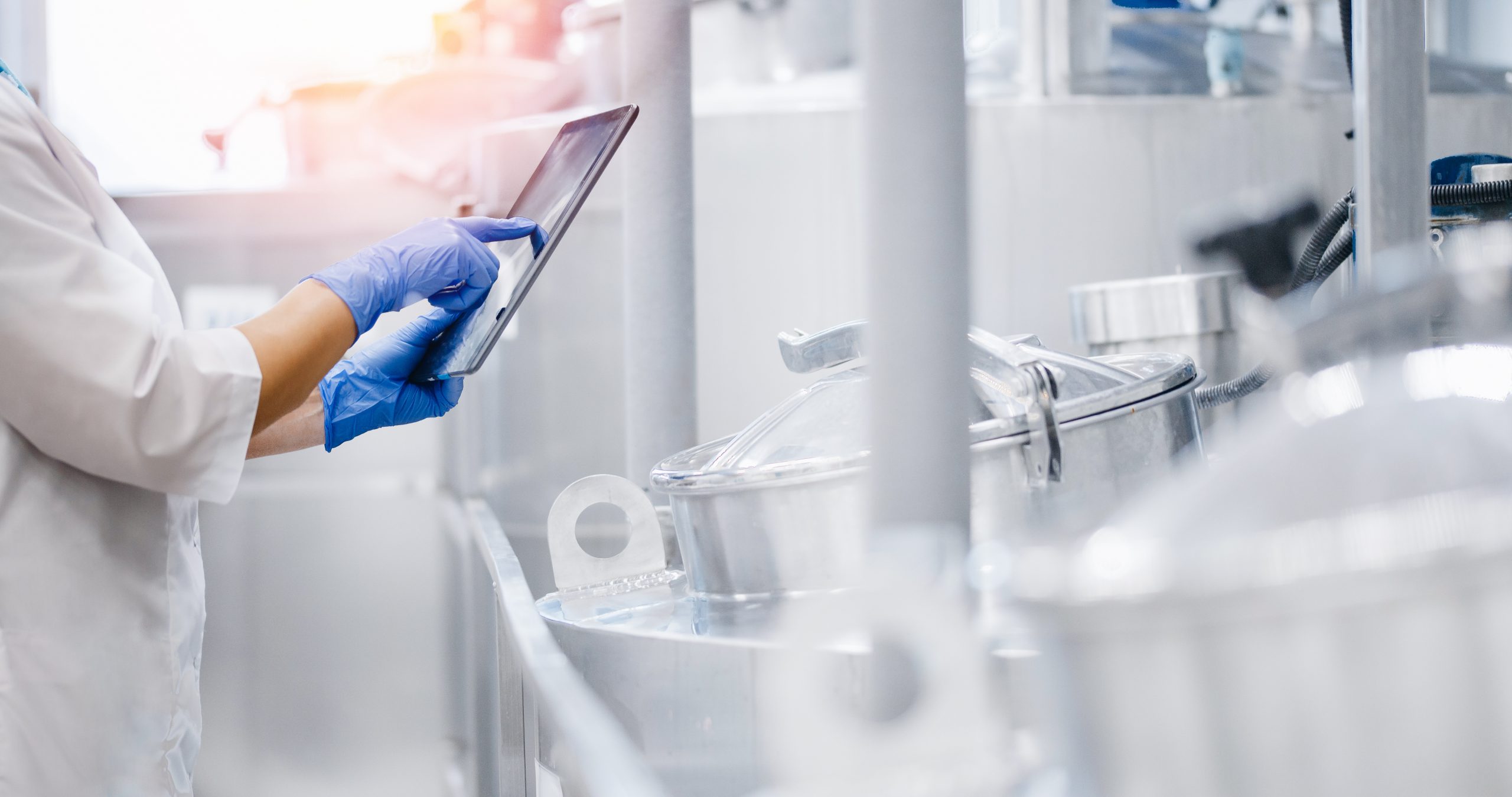 worker with tablet inspecting dairy products in tanks