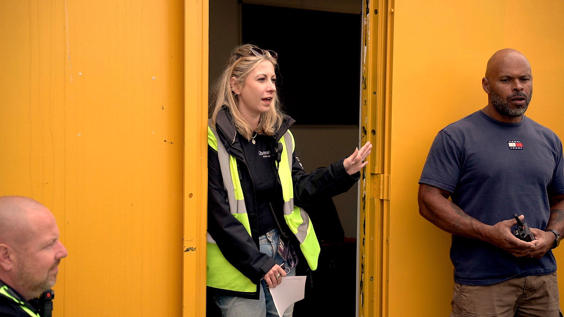 woman wearing high vis vest stands in a yellow doorway