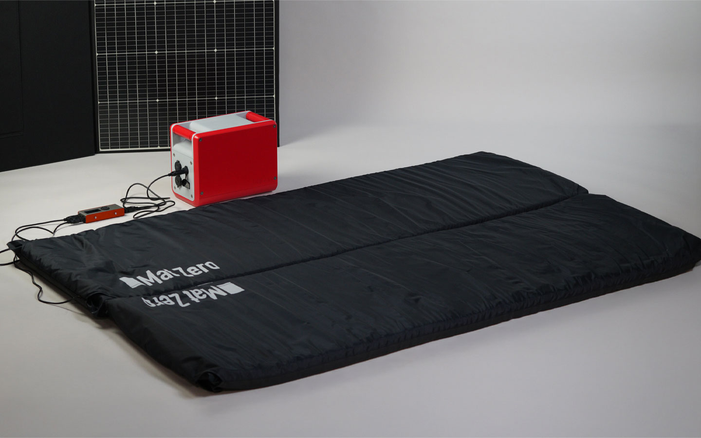 a black heated mat plugged in to a portable battery
